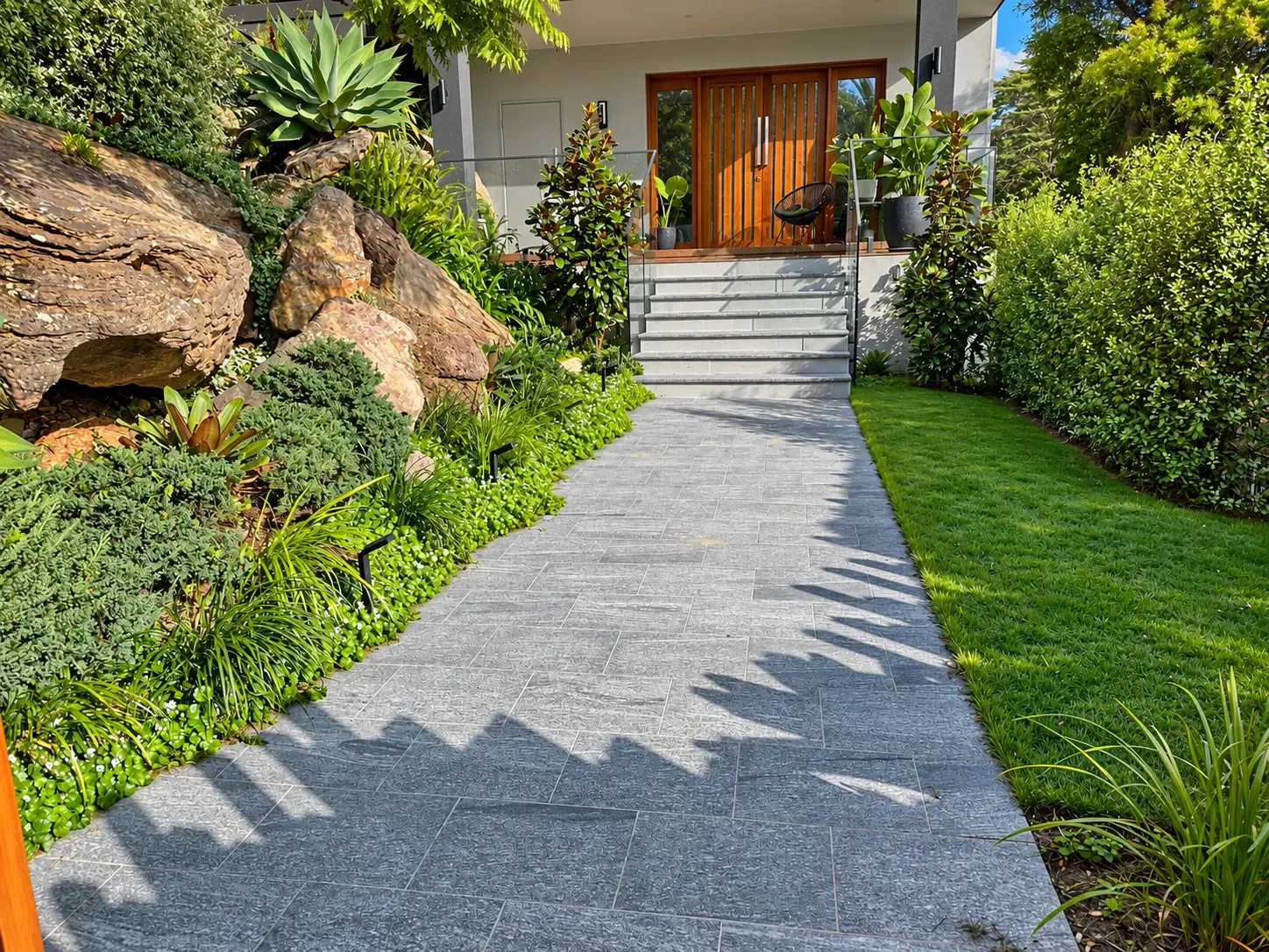 Stone entry path and steps beside exposed sandstone, lush planting and lawn in Mosman