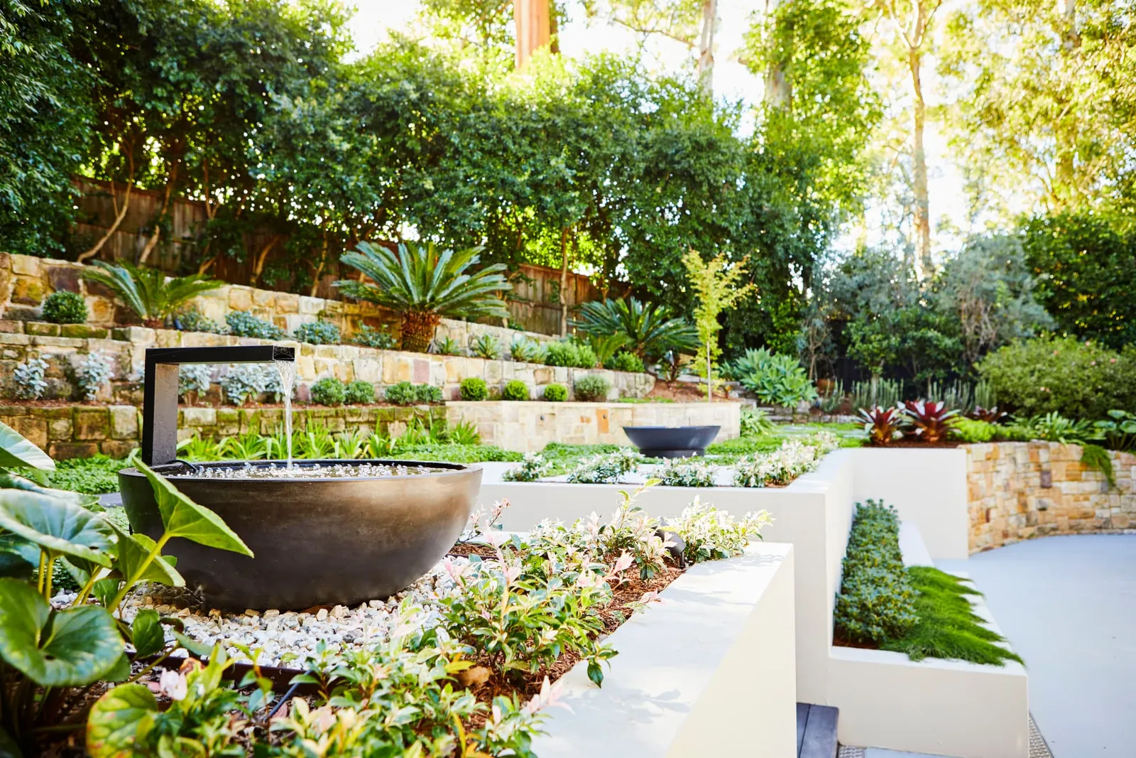 Planted courtyard garden with a stone water bowl and sandstone walls