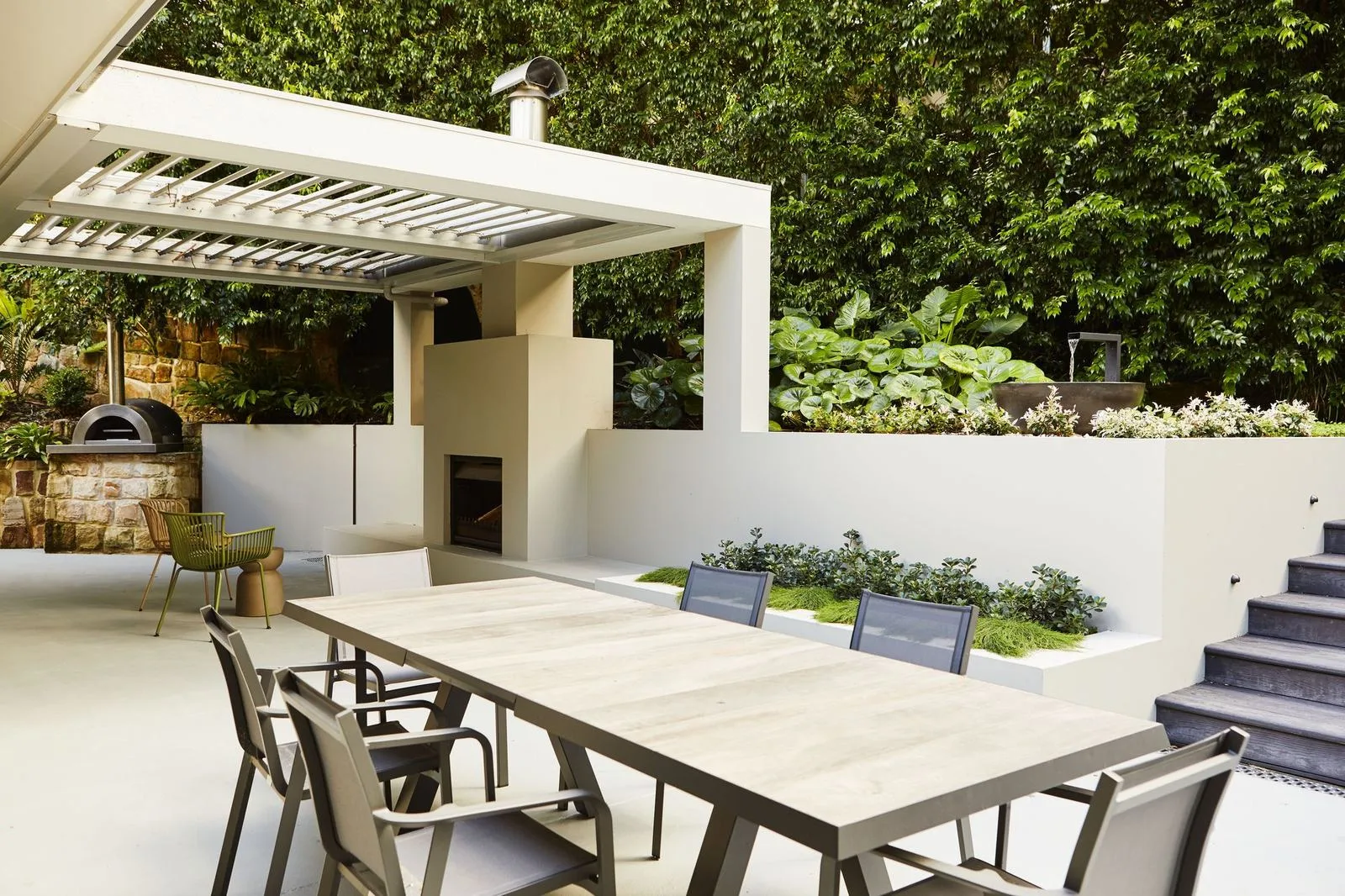 Covered outdoor pavilion and dining terrace with rendered planters in a Pymble garden