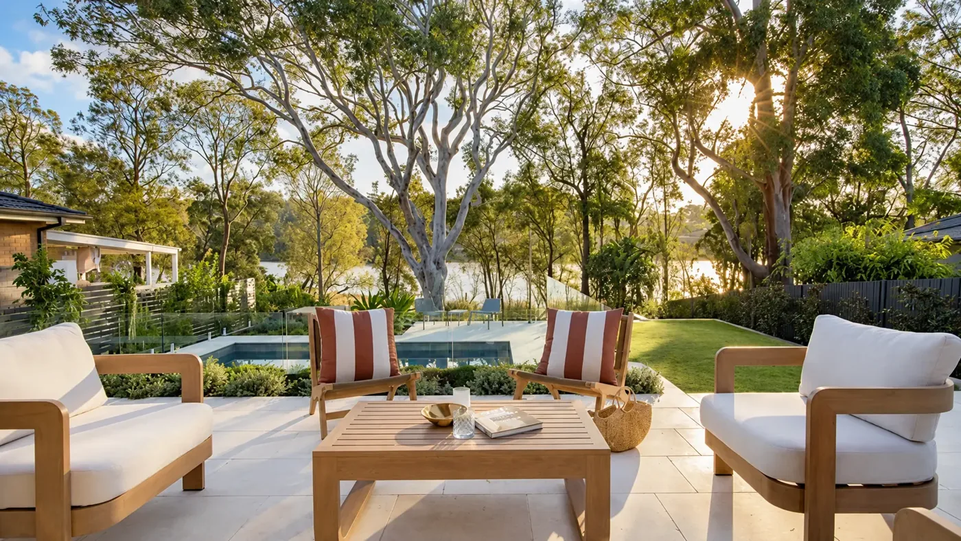 Timber lounge seating on a garden terrace overlooking a swimming pool, lawn and mature trees