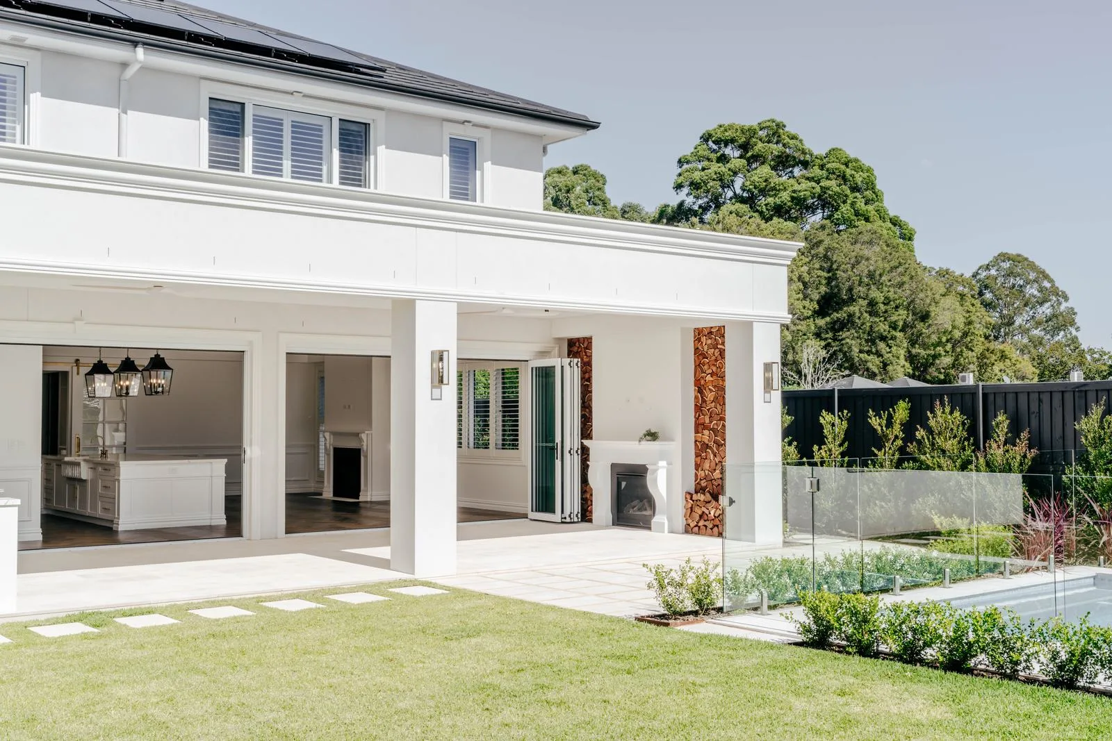 Rear garden with lawn, stepping pavers and pool beside a covered alfresco, Turramurra