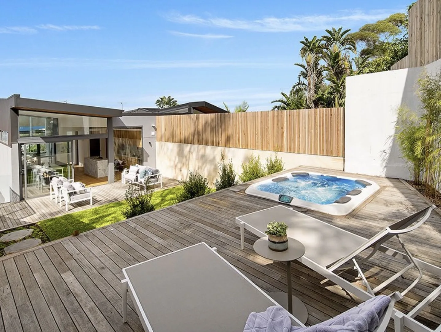 Timber deck with spa, lounge seating and garden walls in a landscaped backyard
