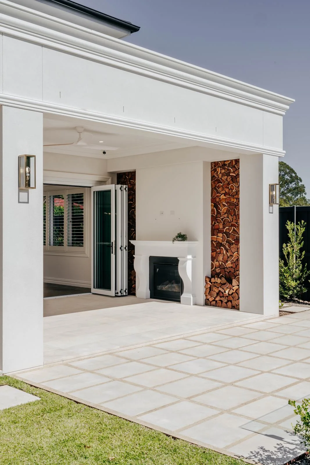 Covered alfresco with outdoor fireplace and pale stone paving