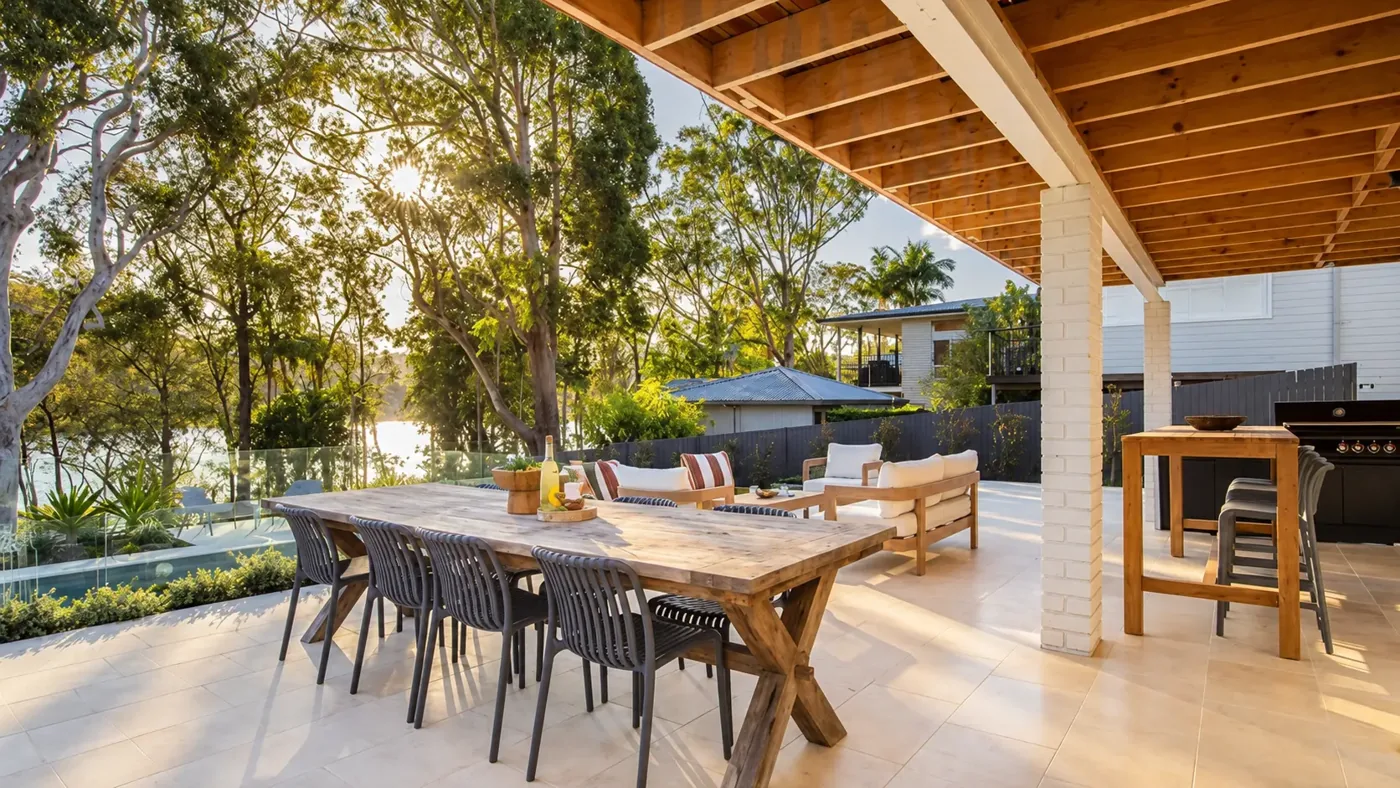 Covered outdoor dining terrace with timber furniture, stone paving and leafy garden views