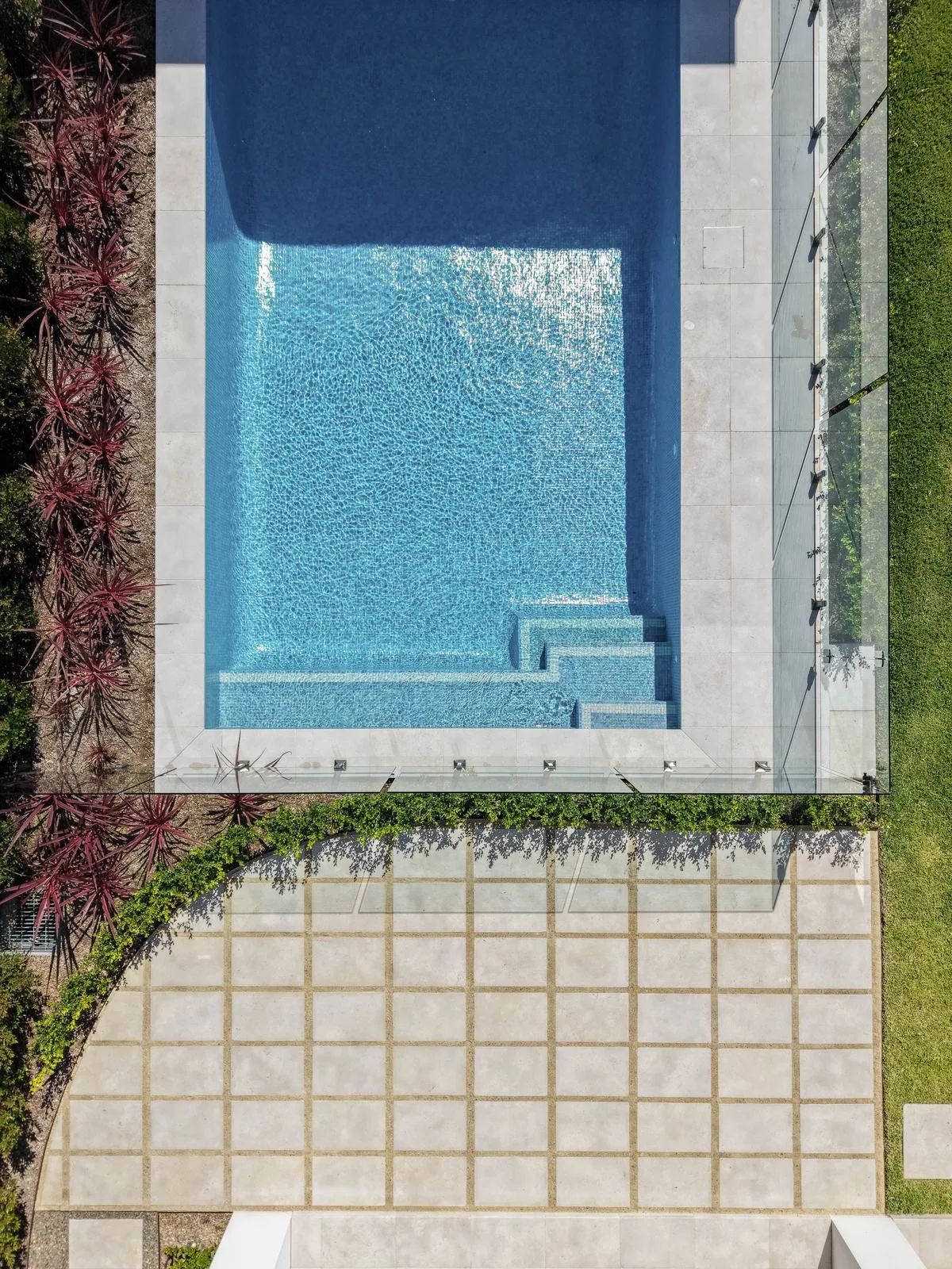 Aerial view of pool landscaping with hedging, Cordylines and stone paving
